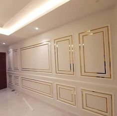 an empty room with white walls and gold trim