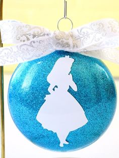 a blue ornament with a silhouette of a woman on it and a white bow