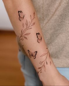 a woman's arm with butterflies on it and leaves around the wrist tattoo design