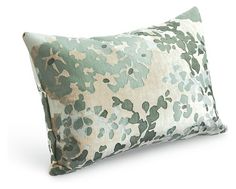 a green and white floral pillow on a white background