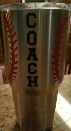 a stainless steel cup with a baseball design on the side and words coach printed on it