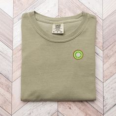 🥝 Trendy Minimalist Kiwi Fruit Sweater 🥝 Indulge in the sweetness of our adorable embroidered mini kiwi fruit tee! Bursting with fruity charm, this delightful piece is the perfect addition to your wardrobe, adding a pop of whimsy and personality to any outfit. 🌟 Features: High-quality embroidery: Our skilled artisans meticulously embroider each mini kiwi fruit design, ensuring vibrant colors and intricate detailing. Comfortable fit: Crafted from soft and cozy fabric, our tee promises all-day Cute Cotton Short Sleeve Sweatshirt, Cute Organic Cotton Crew Neck T-shirt, Organic Cotton Crew Neck Tops With Embroidered Text, Embroidered Organic Cotton Crew Neck Top, Crew Neck Graphic Tee With Fruit Design, Green Embroidered Crew Neck T-shirt, Cute Crew Neck T-shirt With Fruit Design, Green Crew Neck T-shirt With Embroidered Graphics, Trendy Crew Neck T-shirt With Fruit Print