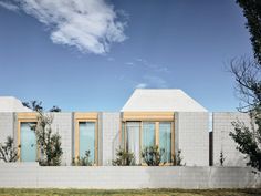 the house is made out of white bricks and has two large windows on each side