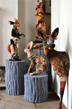 three sculptures are sitting on pedestals in front of a wall and one is decorated with flowers