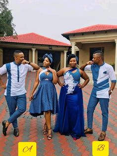 three people standing in front of a house posing for the camera with their arms around each other