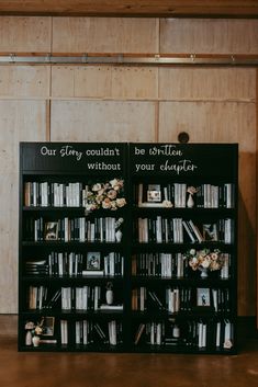 a black book shelf filled with lots of books on top of a wooden floor next to a wall