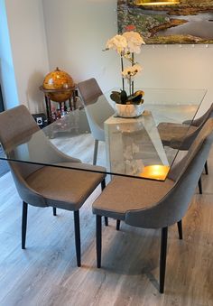 a glass table with chairs around it and a vase filled with flowers on the top