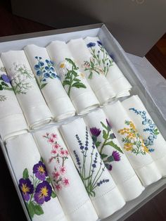 a box filled with white napkins covered in floral embroidered designs on top of each other