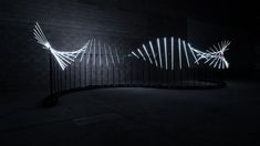 a black wall with white lights on it and a gate in the middle that is lit up