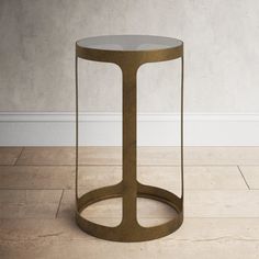 a round metal table with a glass top on the floor in front of a white wall