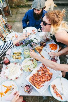 a group of people sitting around a table with food and drinks on top of it