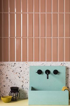 a bathroom sink with two faucets in front of a wall made of tiles