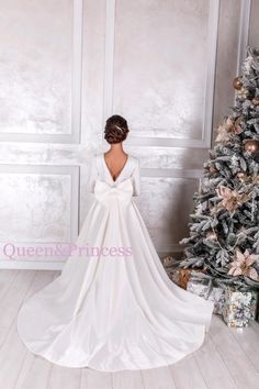 a woman in a wedding dress standing next to a christmas tree