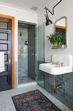 a white sink sitting under a bathroom mirror next to a walk in shower