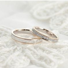 two wedding rings sitting on top of a white blanket