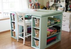 a kitchen island with lots of crafting supplies on the top and bottom shelves in front of it