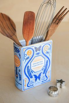 a blue and white box with wooden utensils in it next to some silverware