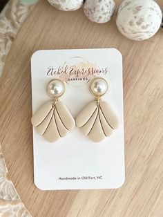 a pair of earrings sitting on top of a wooden table next to some eggs and shells