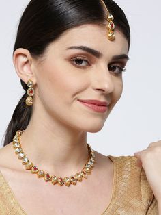 This handcrafted jewelry set consists of a necklace, a maang tikka and a pair of matching drop earrings. The necklace has a maroon color-theme with green accents, comes with kundan stone studs, is gold-plated, and secured with an adjustable drawstring closure. A matching maang tikka comes with kundan stone studs, is gold-plated, and can be secured with a hook closure. A pair of matching drop earrings come with kundan stone studs, are gold-plated, and are secured with a post and back closure. The Gold Plated Kundan Necklace For Temple Jewelry Gift, Temple Jewelry Style Gold Plated Kundan Necklace As Gift, Kundan Temple Jewelry Necklaces For Navratri, Kundan Temple Jewelry Gift, Festive Dual-tone Kundan Necklace For Celebration, Dual-tone Kundan Chandbali Temple Necklace, Gold Plated Kundan Necklace With Meenakari For Puja, Kundan Necklaces With Stone Work For Navratri, Dual-tone Chandbali Kundan Temple Necklace