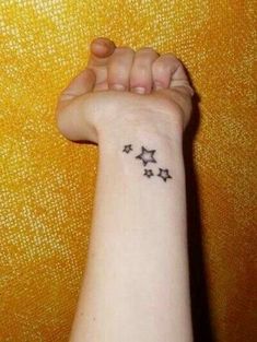 a woman's wrist tattoo with five stars on the left side of her arm