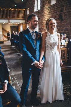 a bride and groom hold hands as they walk down the aisle