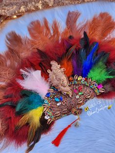 colorful feathers are arranged on top of a white surface with gold and red trimmings