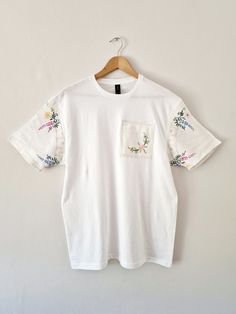 New design to my store ✨️  A plain white 100% cotton classic tshirt in a unisex size Large Unique modern tshirt with added Vintage linen fabrics.  The sleeves are made using a Vintage 1950s linen tablecloth that has delicate hand embroidered designs The patch on the front of the Tshirt is also Vintage 1950s embroidered linen  The tshirt itself is a very soft light cotton  Perfect for the warmer months with shorts or a skirt and then equally perfect for the cooler months under a Cardigan or jacke White Relaxed Fit Organic Cotton T-shirt, Cotton T-shirt With Embroidered Graphics, Crew Neck, Cotton T-shirt With Embroidered Text, Crew Neck, White Embroidered Relaxed Fit T-shirt, Cotton T-shirt With Embroidered Graphics, White Cotton T-shirt With Embroidered Text, White Casual Tops With Custom Embroidery, White Casual Top With Custom Embroidery, White Crew Neck Top With Floral Embroidery