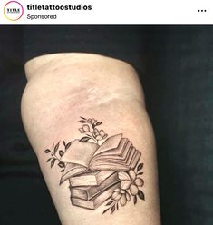 a tattoo with an open book and flowers on it