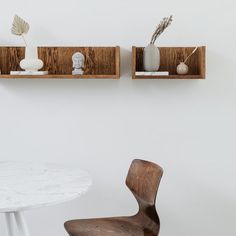 two wooden shelves on the wall above a white table with a chair and vases