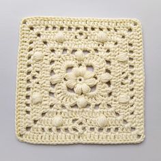 a crocheted square with white flowers on it