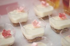 small desserts with white frosting and pink flowers are arranged on a table top