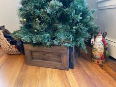 a small christmas tree sitting in a wooden box on the floor next to other ornaments