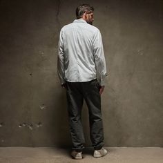 a man standing in front of a wall with his back to the camera and looking at something