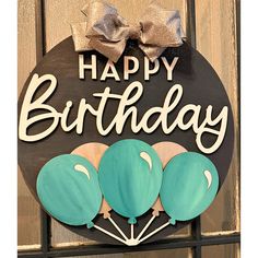 a happy birthday sign hanging on the side of a wooden door with balloons attached to it