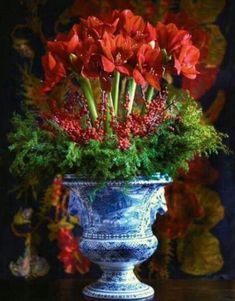 a blue vase filled with red flowers on top of a table