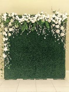 an artificial green wall with white flowers and greenery