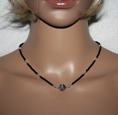 This elegant necklace consists of black Rocailles, Swarovski Crystal beads and silver Miyuki Rocailles. The middle adorns a black pearl, which is equipped with many small sparkling stones. To the right and left of this pearl are 2 crystal pearls with a rhinestone rondel.  Very delicate, light and comfortable to wear, this necklace is a fascinating accessory for special occasions.  The lobster clasp is made of sterling silver 925.  Properties: Rocailles 2.5mm, black and silver  Swarovski Crystal Adjustable Black Pearl Necklace For Party, Elegant Black Pearl Necklace For Weddings, Elegant Black Round Bead Crystal Necklaces, Elegant Adjustable Necklace With Black Beads, Elegant Black Beads Choker As Gift, Elegant Black Beads Choker For Gift, Elegant Crystal Necklaces With Black Beads, Elegant Crystal Necklace With Black Beads For Gift, Elegant Silver Pearl Necklace With Black Beads