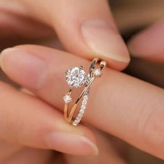 a close up of a person's hand holding a ring with two diamonds on it