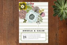 an image of wedding card with flowers on the front and back, sitting next to a succulent plant