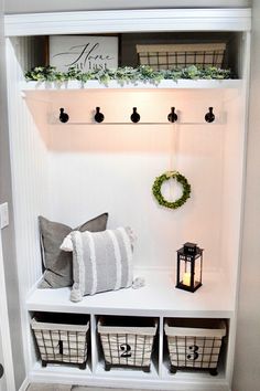 a white shelf with baskets and wreaths on it next to a lantern, lanterns and other items