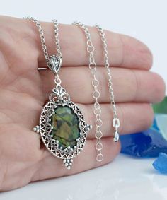 Elevate your style with this stunning handcrafted filigree art pendant necklace. Made with love and care, this necklace features a natural green abalone gemstone that's 13x18mm in size and cut in a cabochon oval shape. The pendant's height is 1.90 inches, and its width is 1.05 inches, making it a striking addition to any outfit. The necklace is 20 inches long and crafted from high-quality silver, ensuring its durability and longevity. Green abalone is a beautiful and unique gemstone that has bee Oval Pendant Necklace, Dragonflies Design, Art Green, Art Pendant, Statement Ring Silver, Sterling Silver Filigree, Sterling Silver Necklace Pendants, Unique Gemstones, Oval Pendant