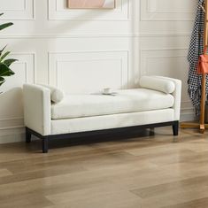 a white couch sitting on top of a hard wood floor next to a potted plant