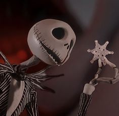 a creepy doll holding a snowflake next to a fake skeleton wearing a striped dress