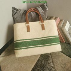 a white and green striped bag sitting on top of a pillow next to a book