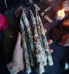 a person holding several candles in their hand next to some other items on the table