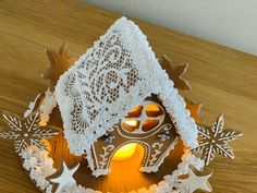 a lit gingerbread house with snowflakes and stars on the roof is sitting on a wooden table