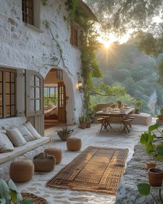 the sun is setting in front of an outdoor living area with couches, tables and potted plants