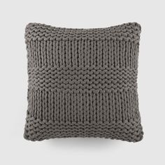 a gray knitted pillow sitting on top of a white wall