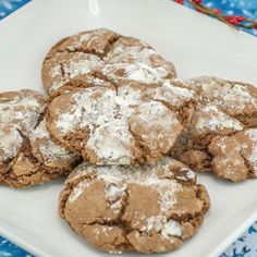 a white plate topped with cookies covered in powdered sugar on top of a blue table cloth