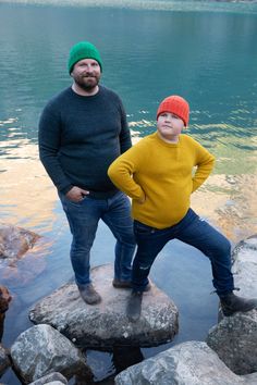 two men standing on rocks in front of water